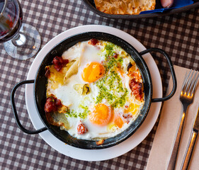 Appetizing Riojan style eggs casserole traditionally prepared with potatoes, bell peppers, sausages and piquant green sauce. Authentic Spanish cuisine