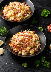 Carbonara fried rice with pancetta, pecorino romano cheese, eggs in a black bowl