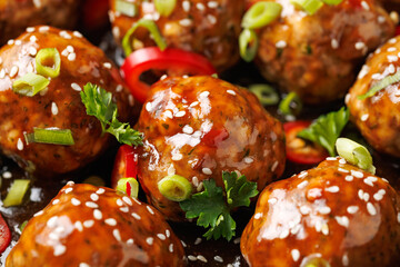 Beef meatballs in teriyaki sauce with sesame seeds, chili and herbs in a cast iron pan