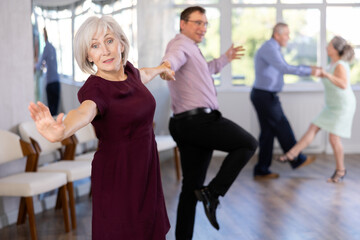 Couple of adult man and elderly woman dancing twist in studio