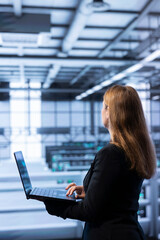 Software developer walking between server rows in data center, doing yearly infrastructure...