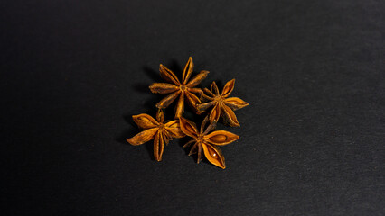 Several star anise pods lie on a black background. Fragrant spices. Star anise. Close up. Copy space.

