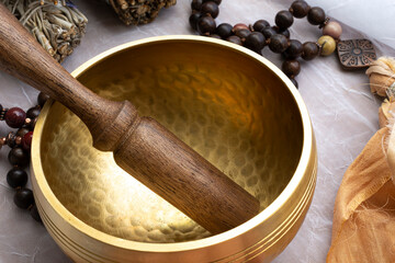 A top view image of a Tibetan singing bowl with wooden mallet and mala beads. 