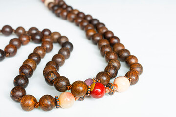 A close image of a strand of wooden mala beads on a white background.
