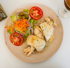 Appetizing grilled sepia served on plate with vegetable salad of greens, tomatoes, carrots and corn. Mediterranean cuisine ..