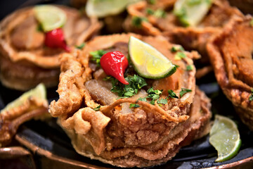 Close-up of fried pork rinds. Crispy pork belly (cracklings). With pepper and lemon on top.