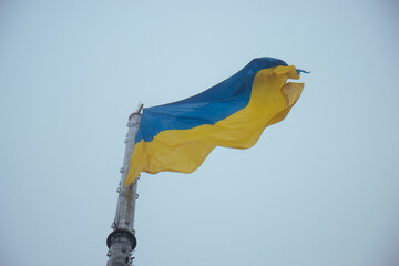 The Ukrainian flag gracefully waving high in the air on a foggy day, its vibrant yellow and blue colors standing as a testament to national resilience and pride.
