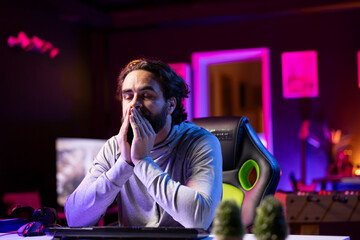 Man feeling tired after working all day, struggling to stay awake while playing games on computer...