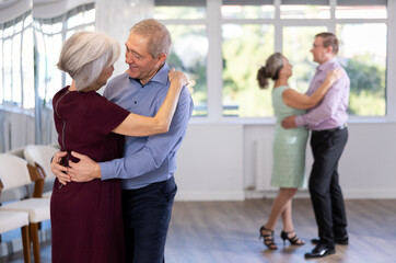 Elderly man and elderly woman dance ballroom dance waltz in studio
