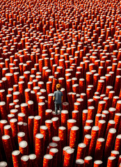 Fototapeta premium A person standing in the middle of a large group of red cylinders