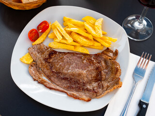 Juicy grilled beef filet steak served with side dish of crispy roasted potatoes and fresh tomatoes..