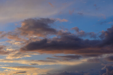 Dramatic evening sky filled with colorful clouds over a tranquil landscape at sunset