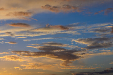 Serene sunset paints the sky in vibrant hues over the horizon with wispy clouds drifting lazily