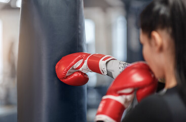 Female boxer in gloves hitting big punching ball during self defence class at gym, copy space