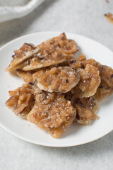 Overhead view of nigerian coconut candy on a white plate, top view of candied coconuts discs, flatlay of bukayo candy or coconut drops