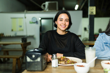 Young lady happily enjoying tasty tacos at an authentic mexican taqueria