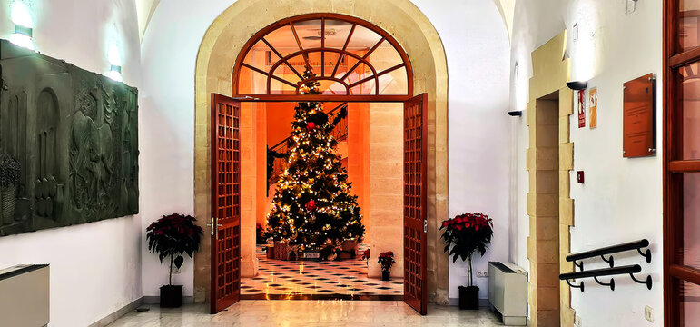 Jerez de la Frontera; zambomba event at the Museo de Belenes with a decorated Christmas tree in a lit hall, surrounded by poinsettias and arched doorways;