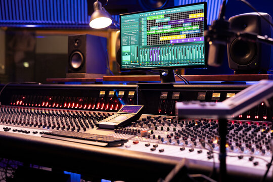 Control desk in professional music studio with motorized faders and knobs used in mixing and mastering tracks. Empty control room used in recording and producing songs, sound booth.