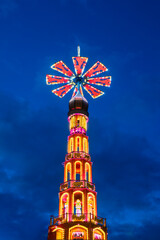Bright large wooden Christmas pyramid during advent season market against night sky