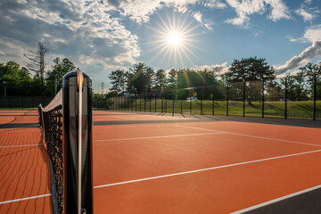 Tennis court net and post on orange and black tennis court - pickleball court with white baseline...