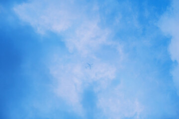 Airplane passing thru blue sky with clouds