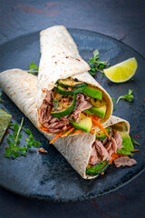Italian style wrap piada wheat tortilla with tuna fish, vegetable and avocado served as closeup on...