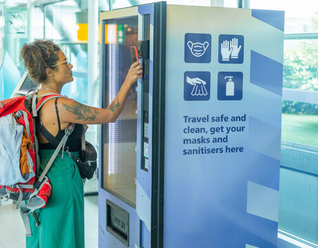 Traveler at airport using vending machine for safety supplies