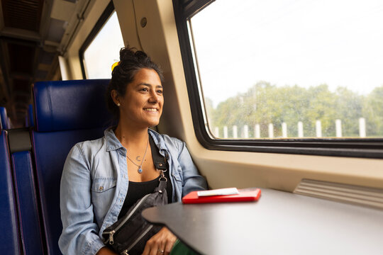 Joyful woman on train journey enjoying scenic landscapes