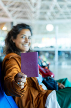 Traveler excitedly displays passport at bustling airport terminal