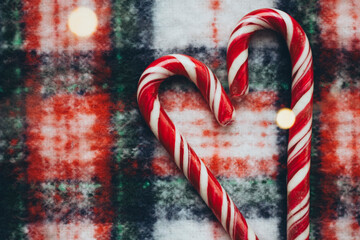Two candy canes forming a heart on a snowy backdrop