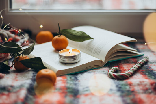 Cozy Christmas vibe with book and burning candle
