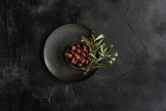 Top view of Greek BBQ olives with fresh herbs on dark plate