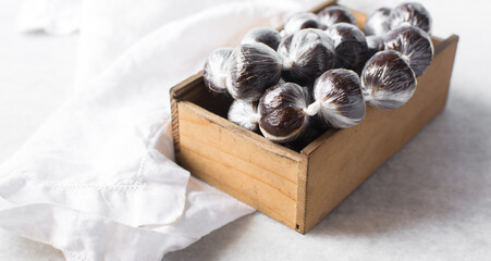 nigerian baba dudu candy in a brown wood box, top view of Ghana coconut candy or kube toffee candy, hard candy made with coconut milk and sugar on granite countertop