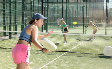Active young woman practicing Padel Tennis with group of players in the tennis court outdoors