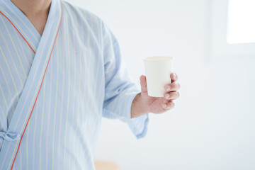 健康診断で尿検査の紙コップを持つ患者