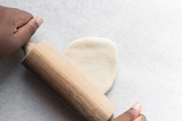 Overhead view of chinese scallion pancake dough being rolled on white countertop, top view of homemade scallion pancakes, process of making cong you bing