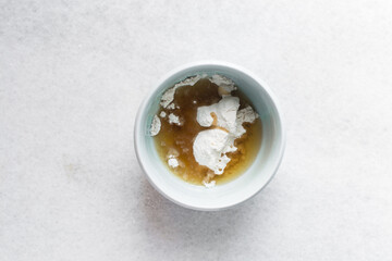 Overhead view of roux in a small bowl, top view of flour and oil mixture in a blue bowl