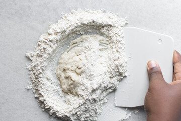 Overhead view of scallion pancake dough being made on a marble countertop, top view of cong you bing dough being mixed, process of making scallion pancakes