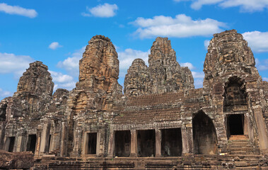 Ancient temple Bayon Angkor complex with stone faces of Buddha in Siem Reap on blue sky cloudy background, Cambodia