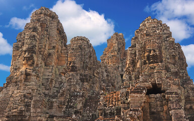 Ancient temple Bayon Angkor complex with stone faces of Buddha in Siem Reap on blue sky cloudy background, Cambodia