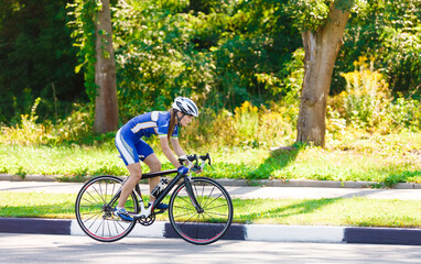 Female sportsman cyclist riding racing bicycle. Woman cycling on countryside summer sunny road or highway. Training for triathlon or cycling competition.