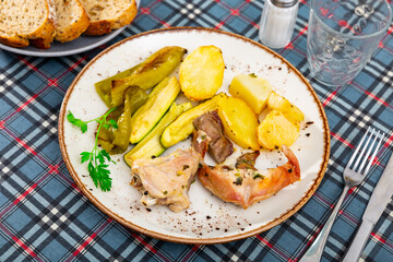Appetizing baked young rabbit served with potato and grilled pepper and courgette