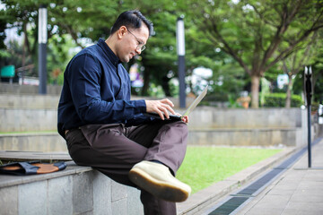 Obraz premium Portrait of Man In Semi Formal Style Working Using Laptop While Sitting on Bench