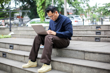 Portrait of Businessman Sitting on Stairs Working Using Laptop