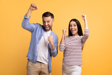 Two excited individuals express their affection and joy with raised arms and big smiles against a...