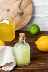 Limes and lemons syrups in glass bottles and cutting board on background.