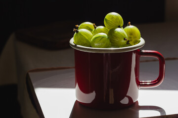 Gooseberries in a red mug and natural sunlight