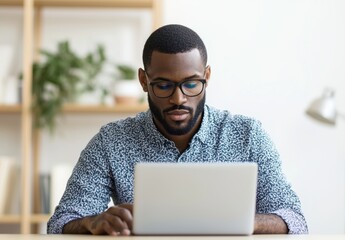 Focused young man working on laptop in a bright modern workplace