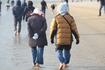 Image of people walking barefoot at Dadaepo Beach in Busan

