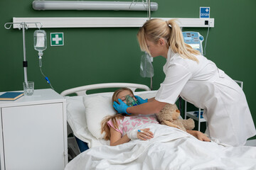 A caring nurse assists a child in a hospital bed with an oxygen mask, ensuring their wellbeing